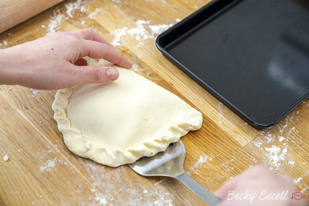 Using a spatula, transfer your gluten free calzone to a baking tray using a spatula or something similar