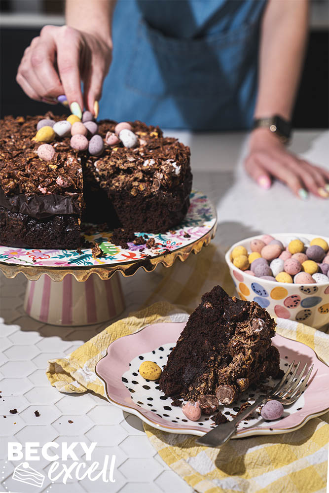 A BTS shot of topping the finished cake with one slice taken displayed on a plate in front