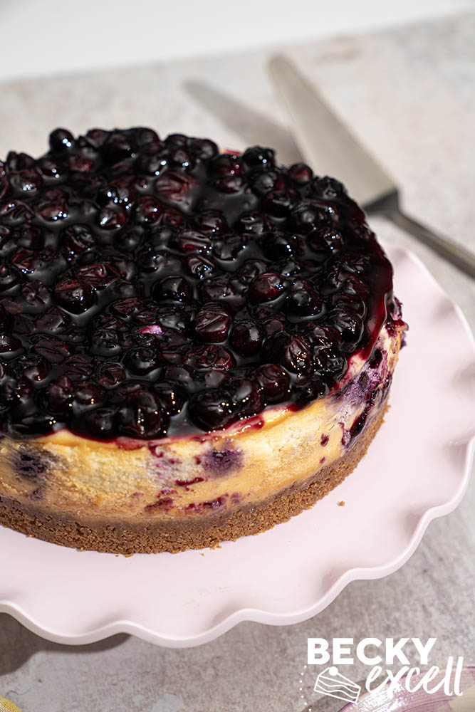 The finished baked cheesecake on a cake stand, unsliced