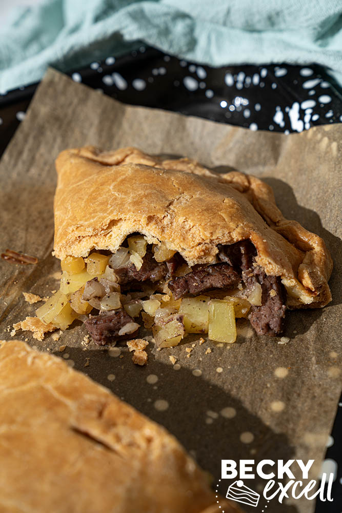Close-up of a sliced Cornish pasty with golden gluten-free pastry and chunky beef and potato filling