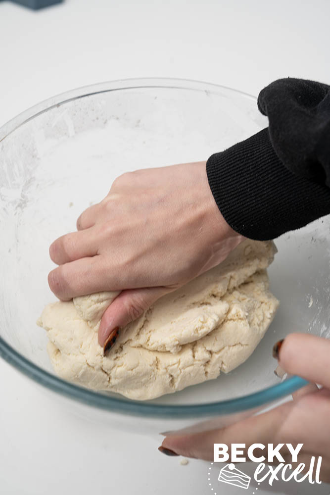 Using hands to squeeze the dough together into a ball