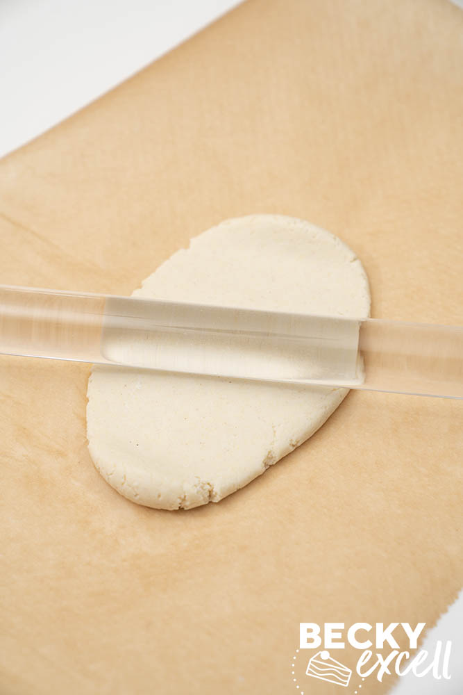 Rolling out the dough portions one at a time on non-stick baking paper