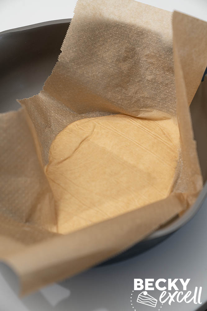 Inverting the rolled out dough into the hot pan using the baking paper to lift it in